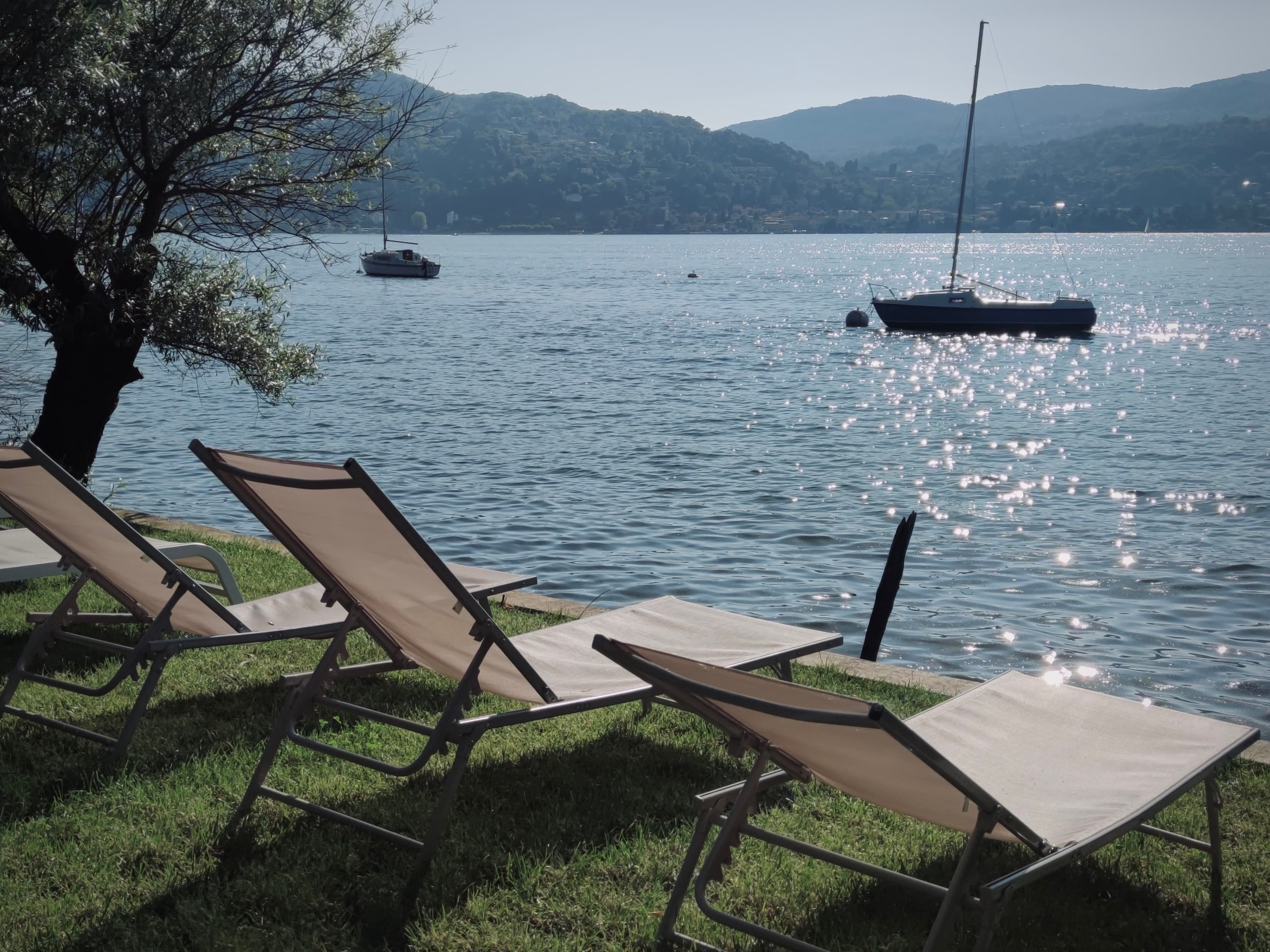 Sun loungers on a lawn beside open water